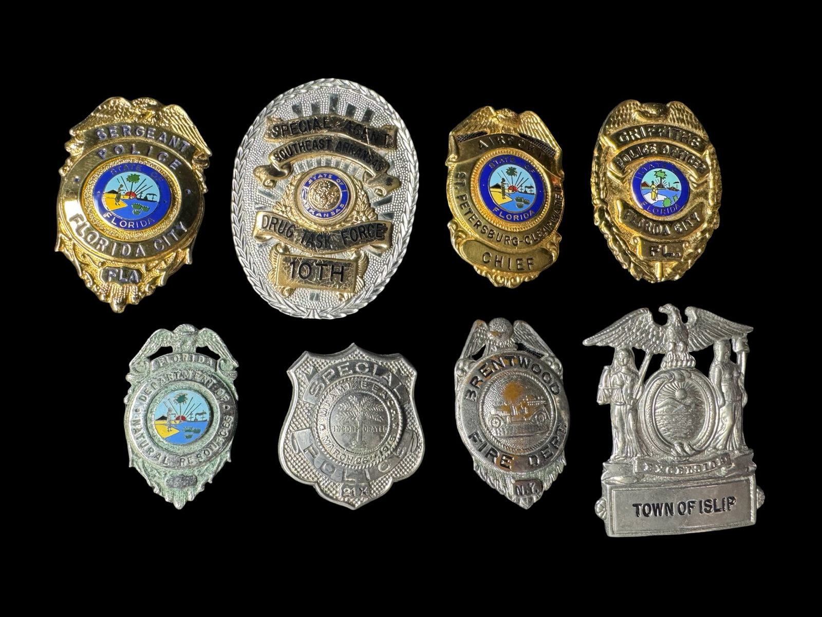 Obsolete Police Badge Assortment: This vintage police badge assortment includes the Town of Islip, Brentwood, Florida City, and more. There is a total of eight gold tone and silver tone badges. The largest badge measures 3.25 inches h