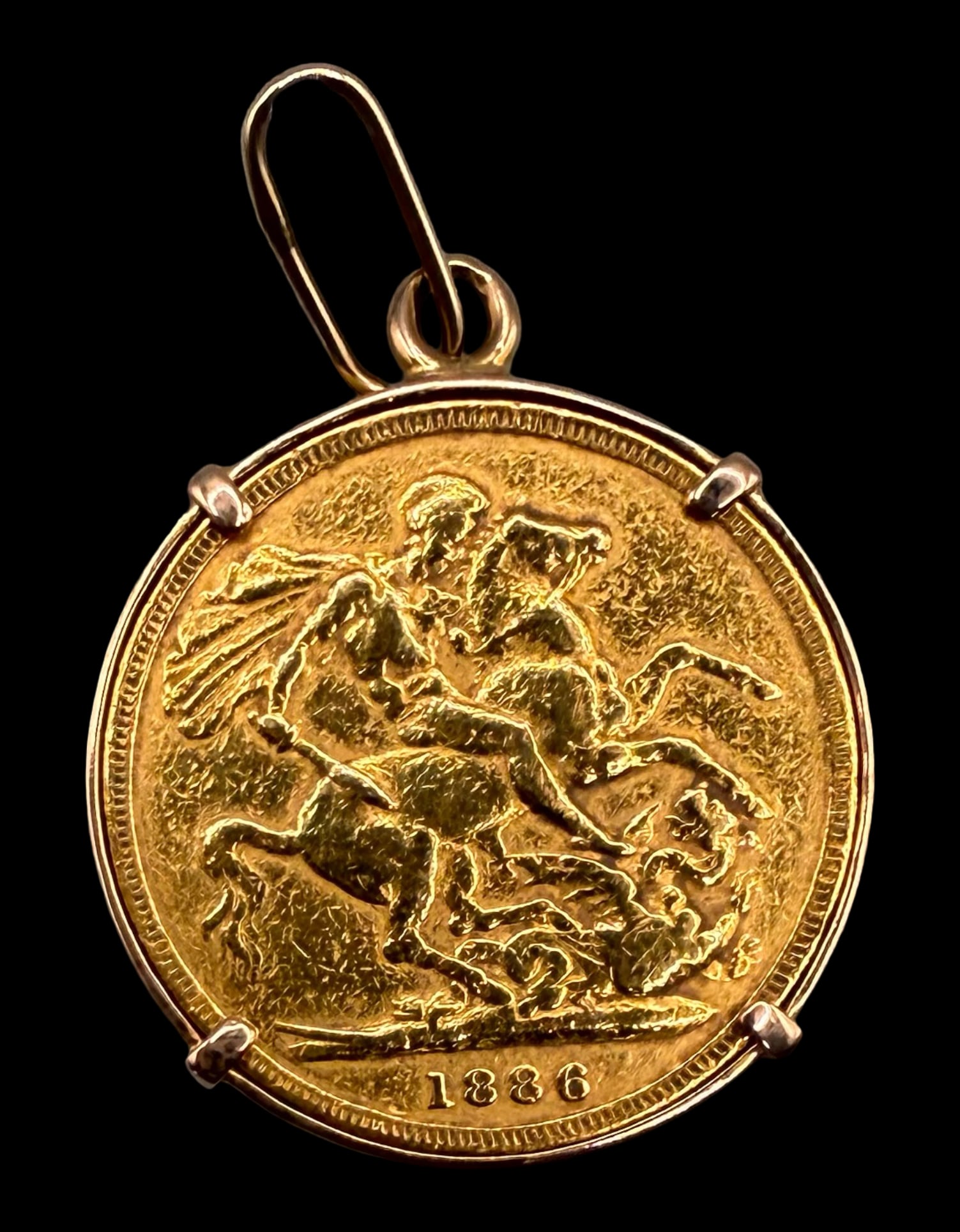 1886-M British Full Gold Sovereign in Bezel: This full gold sovereign was struck at the Melbourne Mint in Australia in 1886. It features William Wyon’s “Young Head” left-facing bust of Queen Victoria on the obverse, and St. George on h