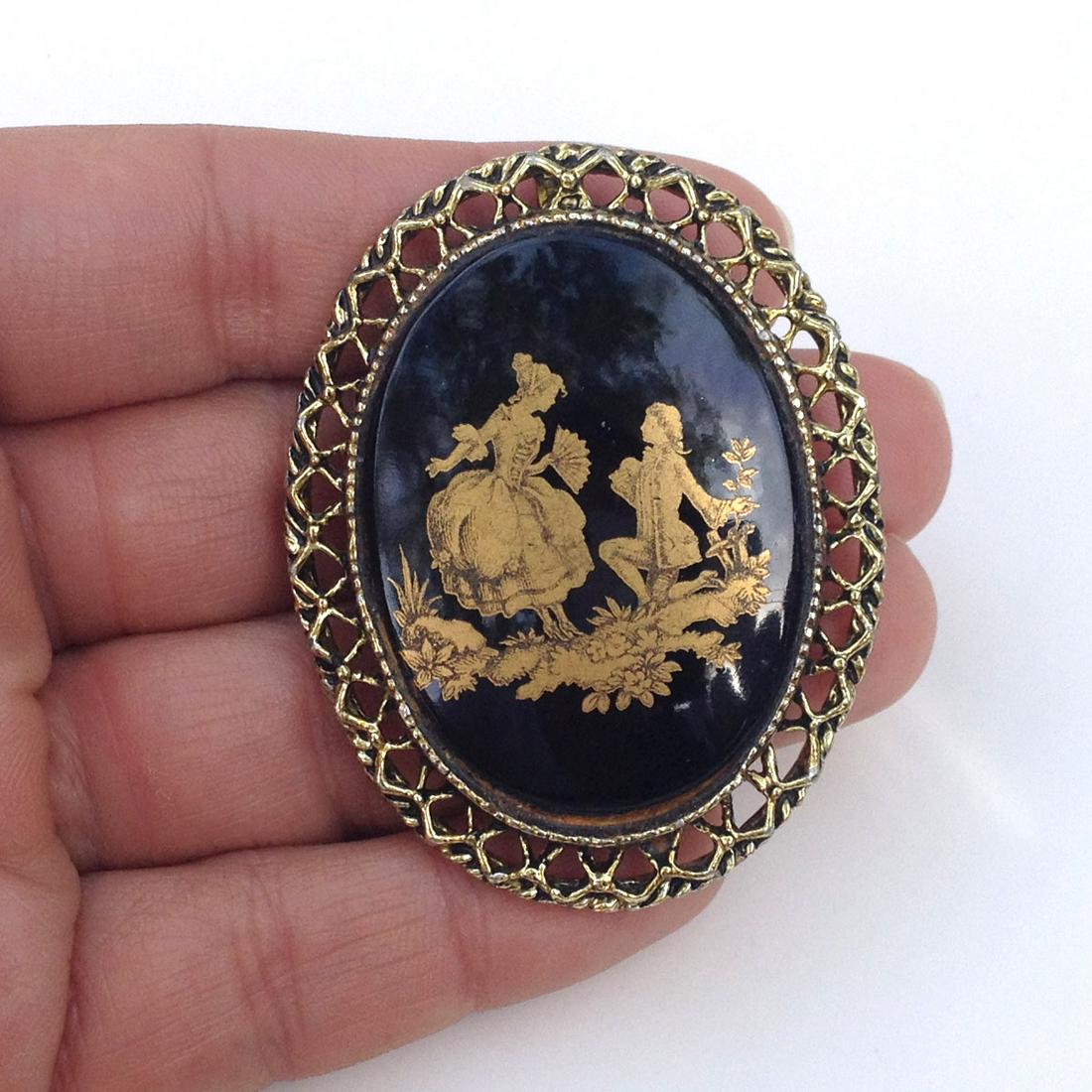 Gold tone and black oval brooch pendant: Gold tone oval shape brooch pendant with gold print on black shiny background. Measured 2 x 1 1/2 inches. Condition excellent.