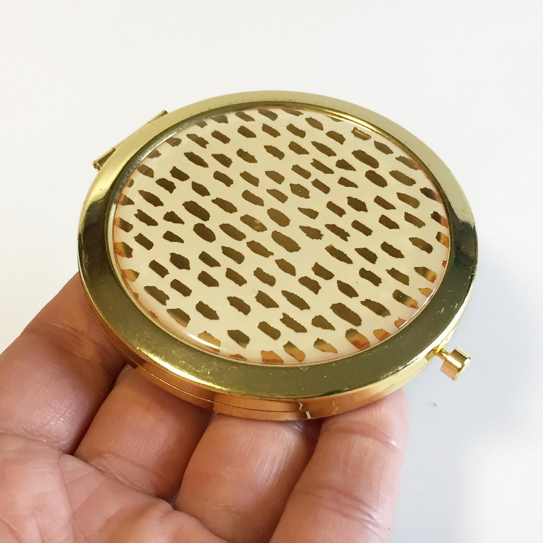 Gold tone ivory design round compact mirror: Gold tone ivory design round compact mirror. Measured 2 3/4 inches in diameter. Condition good.