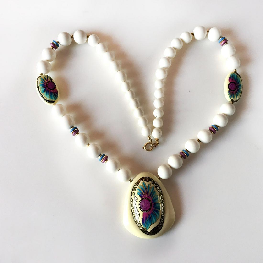 Vintage white blue purple gold painted necklace: Vintage white round beads with blue purple gold painted beads and pendant necklace. Pendant length 2 3/8 inches, necklace length 25 inches. Condition excellent.