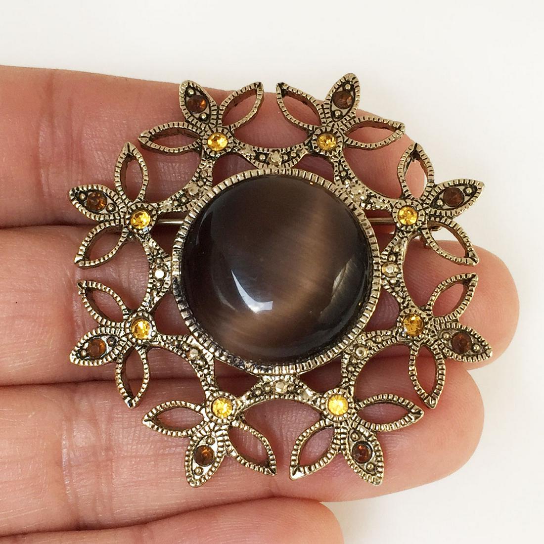Gold tone brown cat eye color cab round Flower brooch: Gold tone textured finish round shape brown cat eye color cab, orange and brown crystals round Flower brooch. Measured 2 inches in diameter. Condition very good.