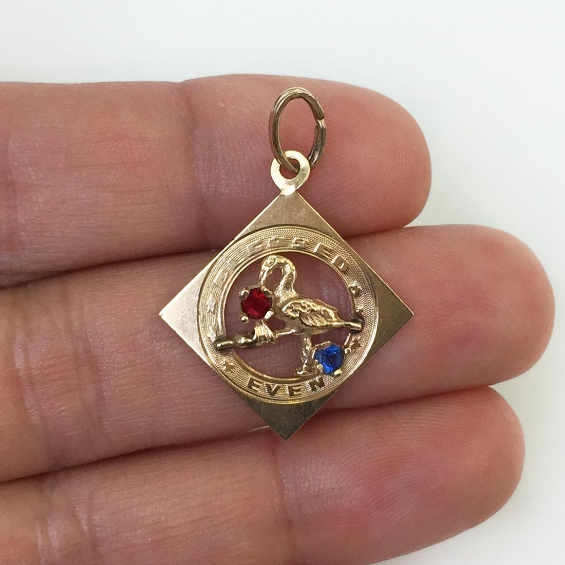 14KT gold ruby sapphire stork baby born pendant: 14KT yellow gold textured finish round faceted ruby and sapphire stork "blessed event" baby born newborn pendant. Weight 1.24 grams. Hallmarked 14 KT. Length 1 1/4 inches with bail. Condition very goo
