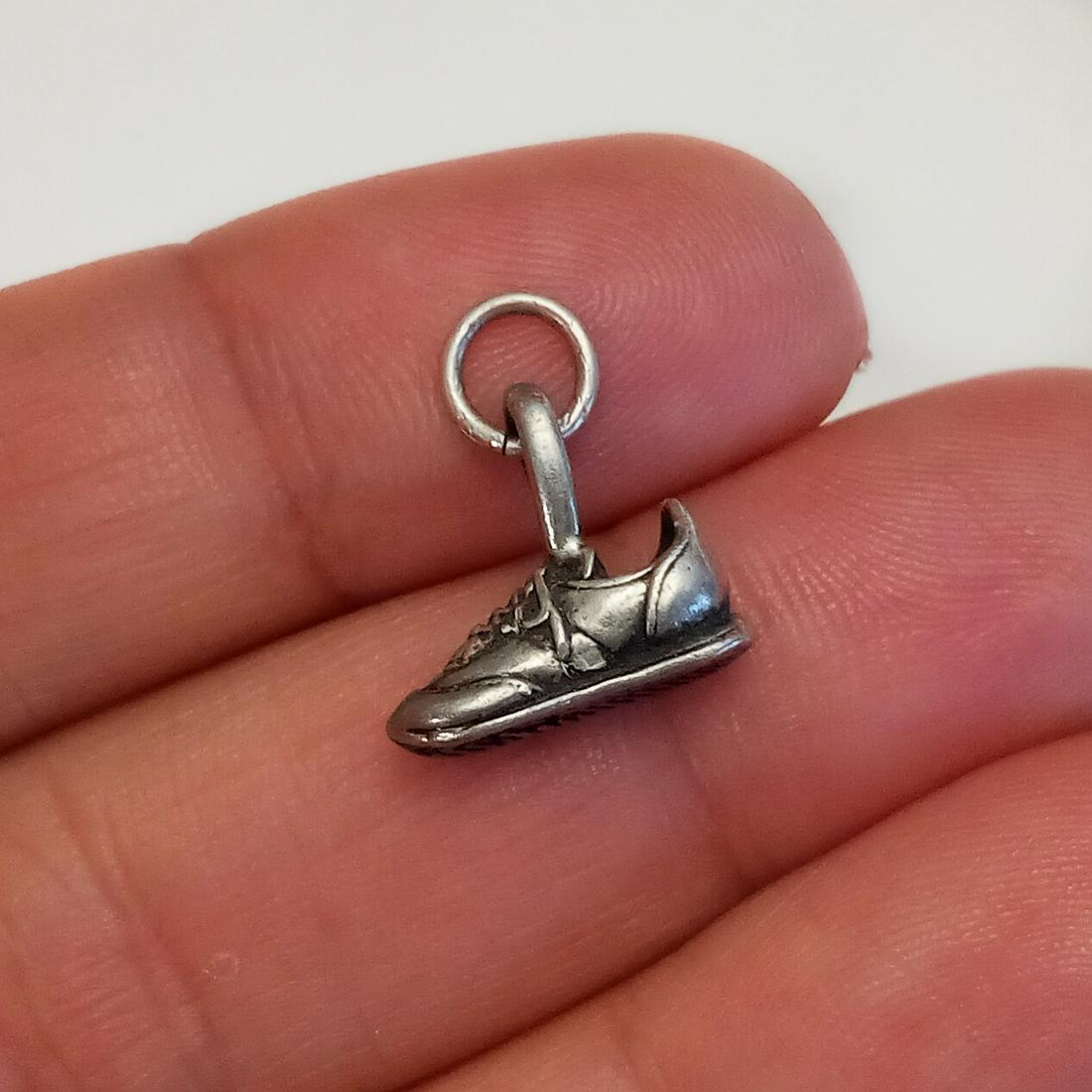 Vintage sterling silver Sneaker Shoe pendant charm: Vintage sterling silver Sneaker Shoe pendant charm. Weight 1.94 grams. Length 5/8 inches with bail. Hallmarked © Ster flower symbol. Condition very good.