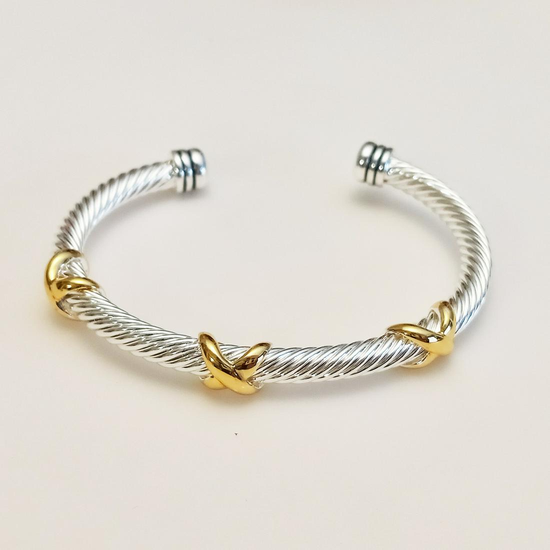 Two tone David Yurman Style X cable cuff bracelet: Silver tone and gold tone twisted cable texture David Yurman Style X accent cuff bangle bracelet. Thickness measured 3/16 inches. Inside measured 2 3/8 x 1 7/8 inches. Condition excellent.