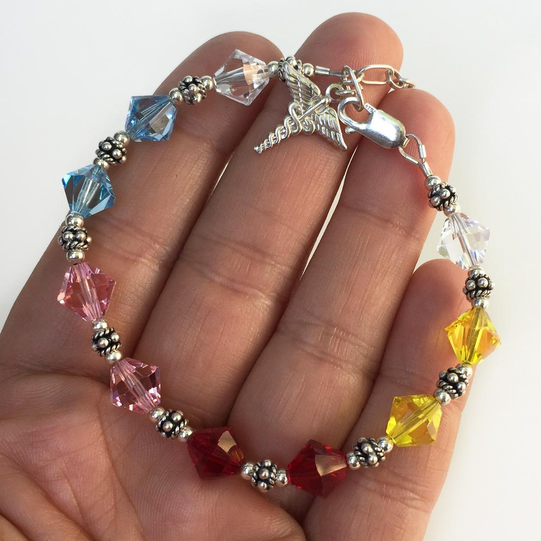 Sterling silver faceted beads charm bracelet: Sterling silver faceted fancy shape beads Caduceus medical charm bracelet. Beads colors are: clear, yellow, ruby red color, pink topaz color, blue topaz color. Length 7 1/4 inches + 1 1/2 inches exten