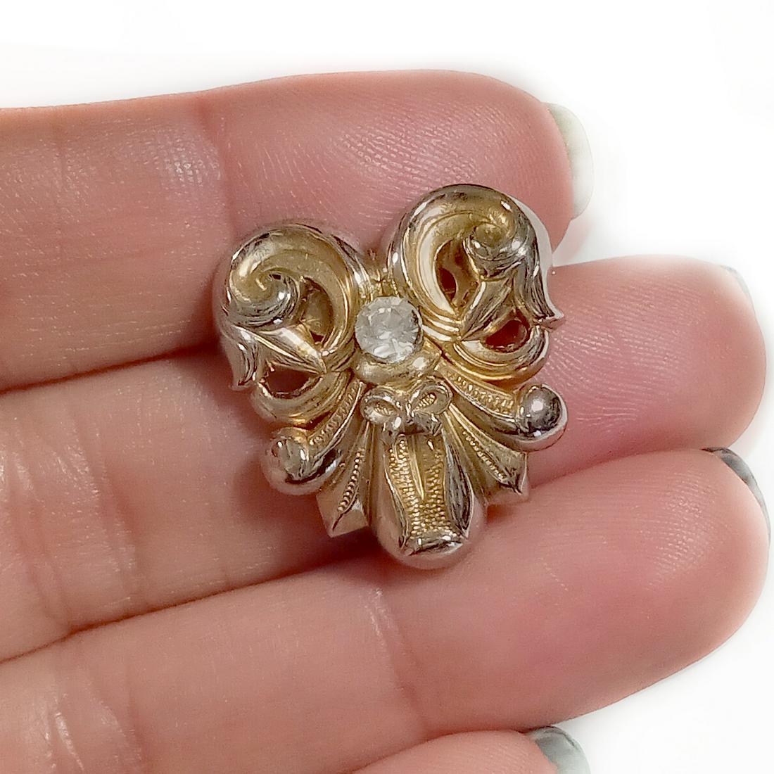 Vintage gold tone rhienstones heart bow brooch: Vintage gold tone textured finish clear rhinestones heart and bow brooch. Measured 3/4 x 7/8 inches. Condition very good.