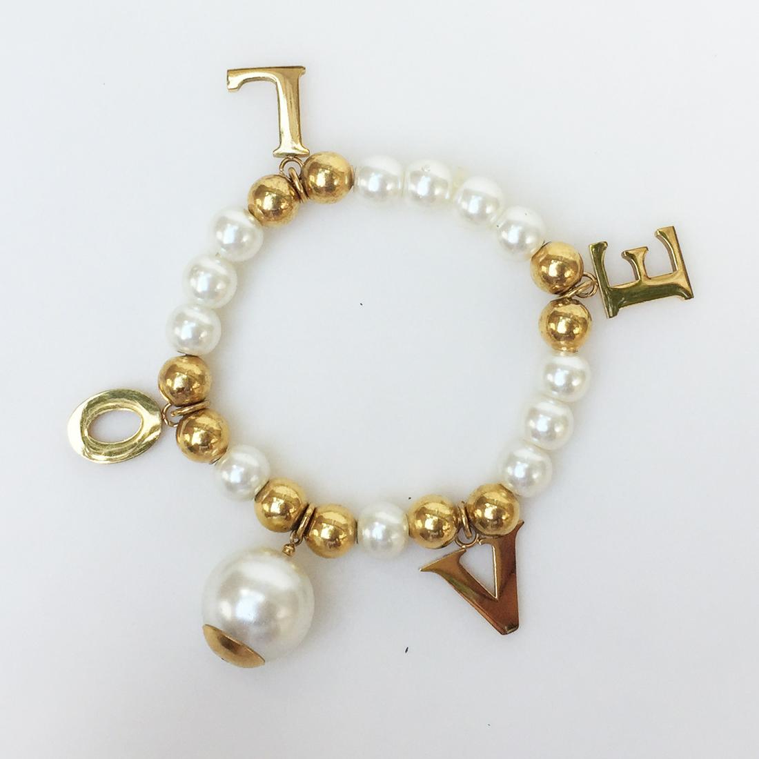 Gold tone faux white pearl LOVE stretch bracelet: Gold tone beads and faux white pearl LOVE stretch bracelet. Bracelet stretches from 6 inches to 7 1/2 inches. Charms length 5/8 inches. Gold tone beads and faux pearls measured 8 mm in diameter. Condi