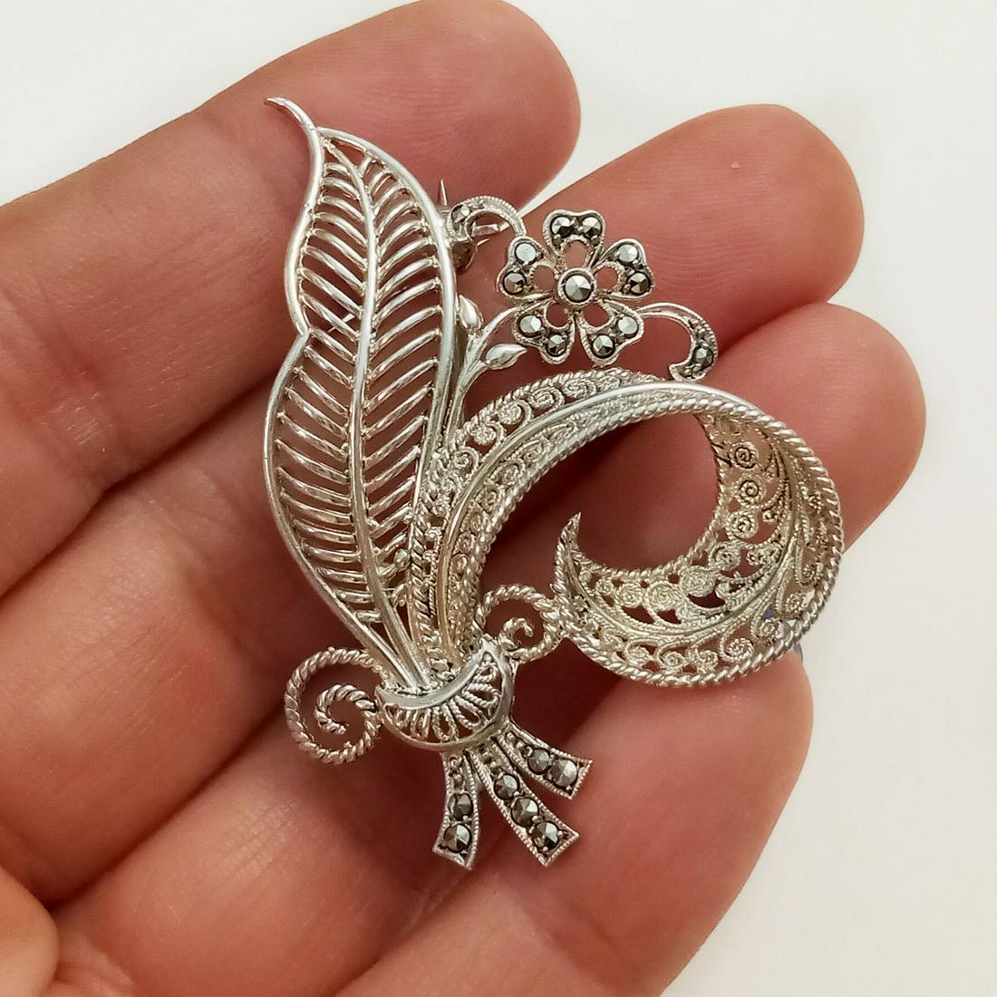 Sterling silver marcasites Flower brooch: Sterling silver filigree texture marcasites Flower Leaf brooch. Weight 6.02 grams. Measured 1 3/4 x 1 1/4 inches. Hallmarked Sterling ON. Condition very good.