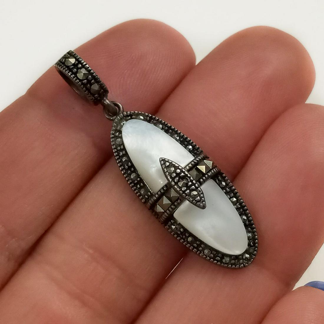 JC Vintage sterling silver MOP marcasites pendant: JC Vintage sterling silver white Mother of Pearl and marcasites pendant, signed. Weight 3.89 grams. Length 1 1/2 inches with bail. Hallmarked JC, 925. Condition very good.