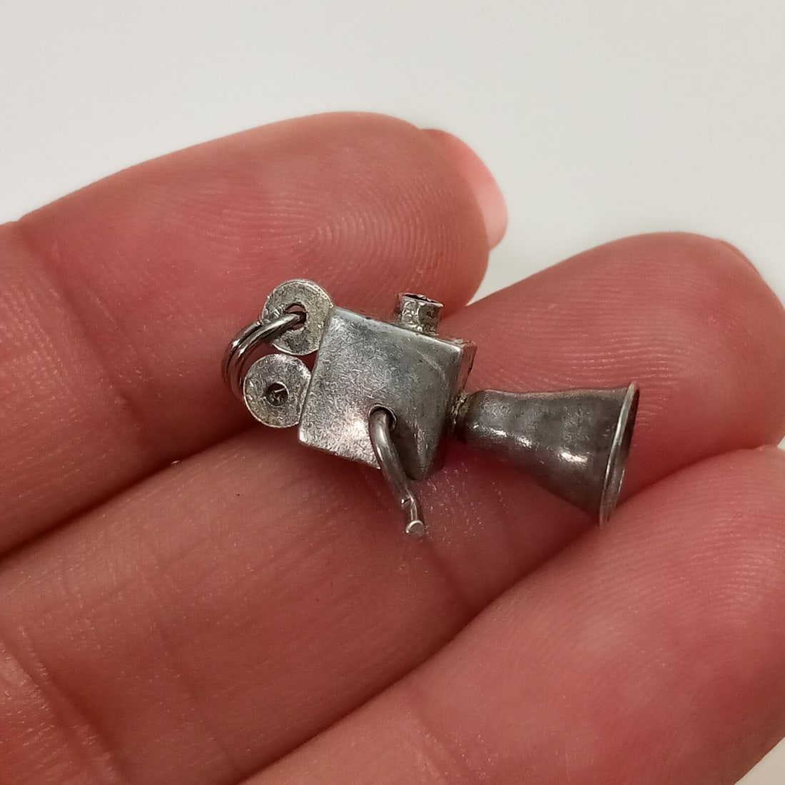 Vintage sterling silver movie camera charm: Vintage sterling silver movie camera charm with turning handle. Weight 1.50 grams. Length 7/8 inches with bail. No hallmark, charm tested 925 sterling silver. Split ring bail is silver tone. Condition
