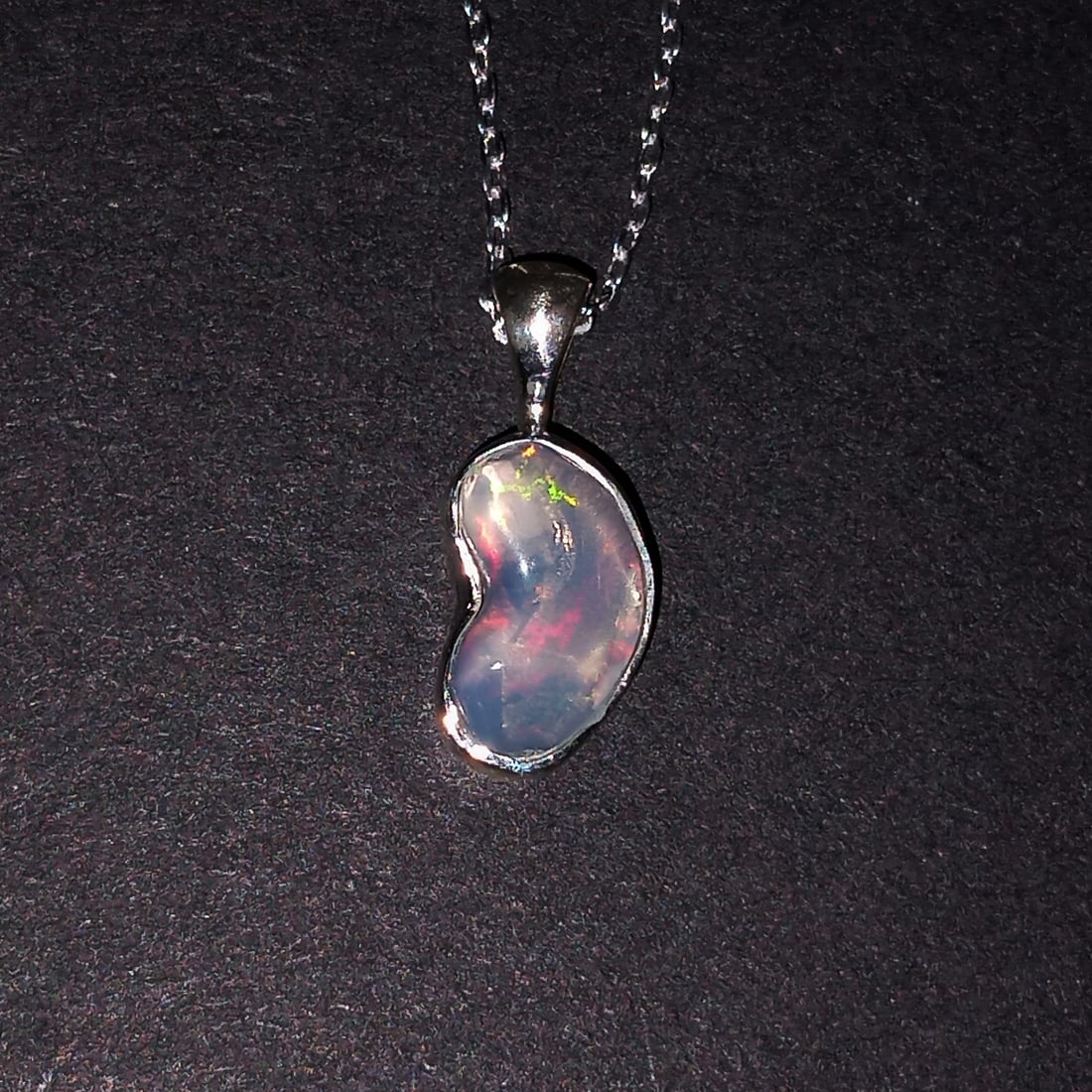Sterling silver free shape polished Ethiopian opal pendant and chain necklace: Sterling silver free shape polished Ethiopian opal pendant and chain necklace. Opal has very nice play of color. Chain length can be worn as 16 inches and 18 inches. Pendant length 5/8 inches with bai