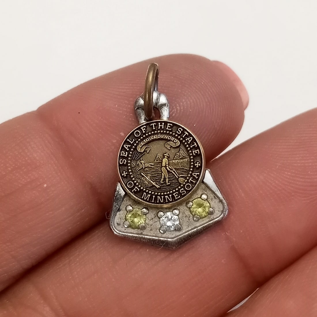 CTO Sterling silver Minnesota State Seal charm: CTO Sterling silver and gold tone, clear and yellow rhinestones Seal of the state of Minnesota, signed. Weight 2.28 grams. Length 3/4 inches with bail. Hallmarked CTO Sterling. Front part and bail are