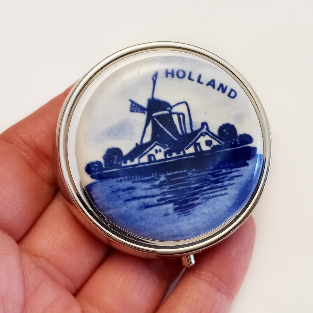 Silver tone painted ceramic blue mint pill box: Silver tone painted ceramic blue Holland Windmill round shape mint pill box. Measured 2 inches in diameter. Condition very good.