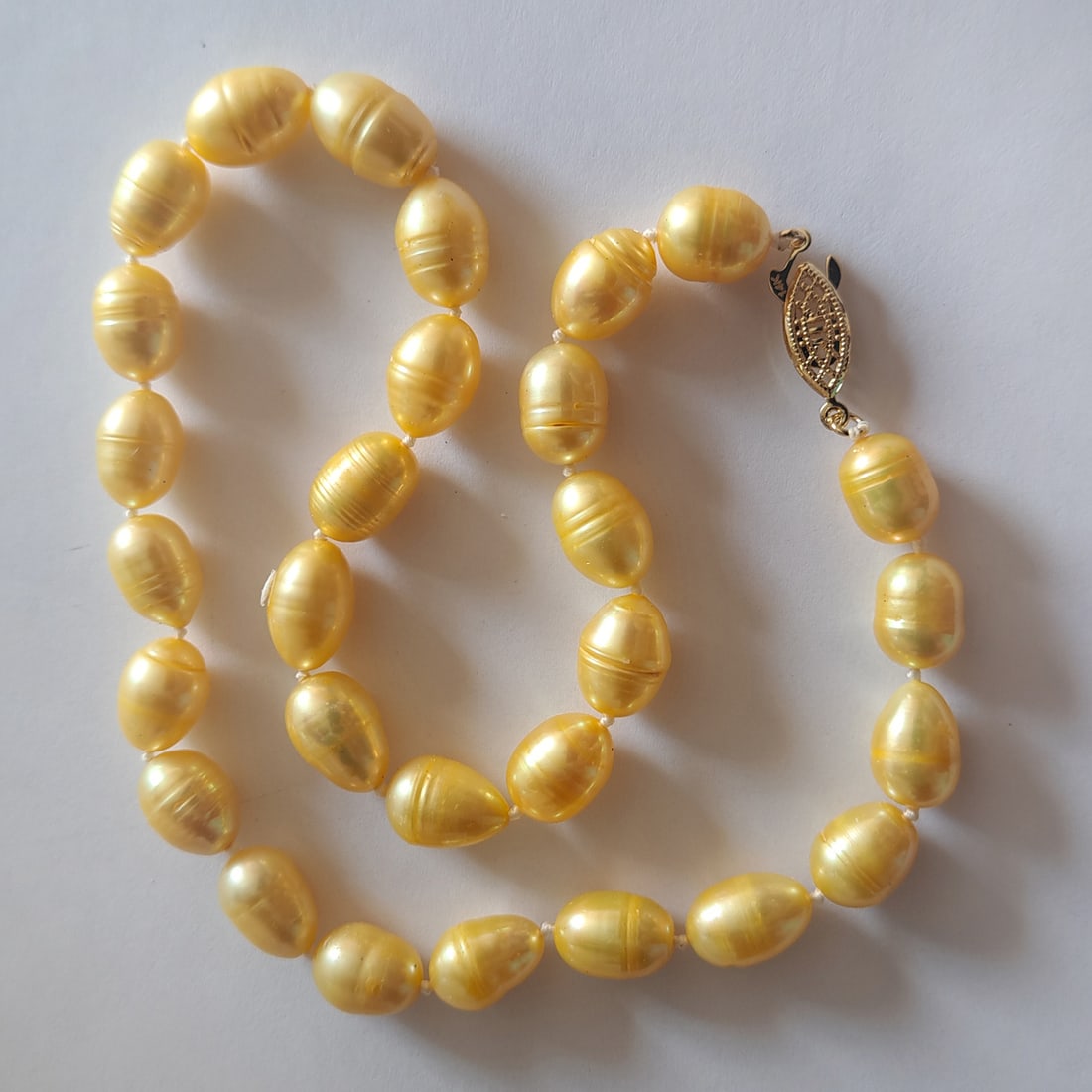 Natural gold South Sea baroque knotted pearl necklace with gold tone fish clasp, 18": Natural gold yellow South Sea baroque knotted pearl necklace with gold tone fish clasp. Pearls measured approx. from 10 mm x 12 mm to 11 mm x 15 mm. Pearls are very well matched in color, shape and si