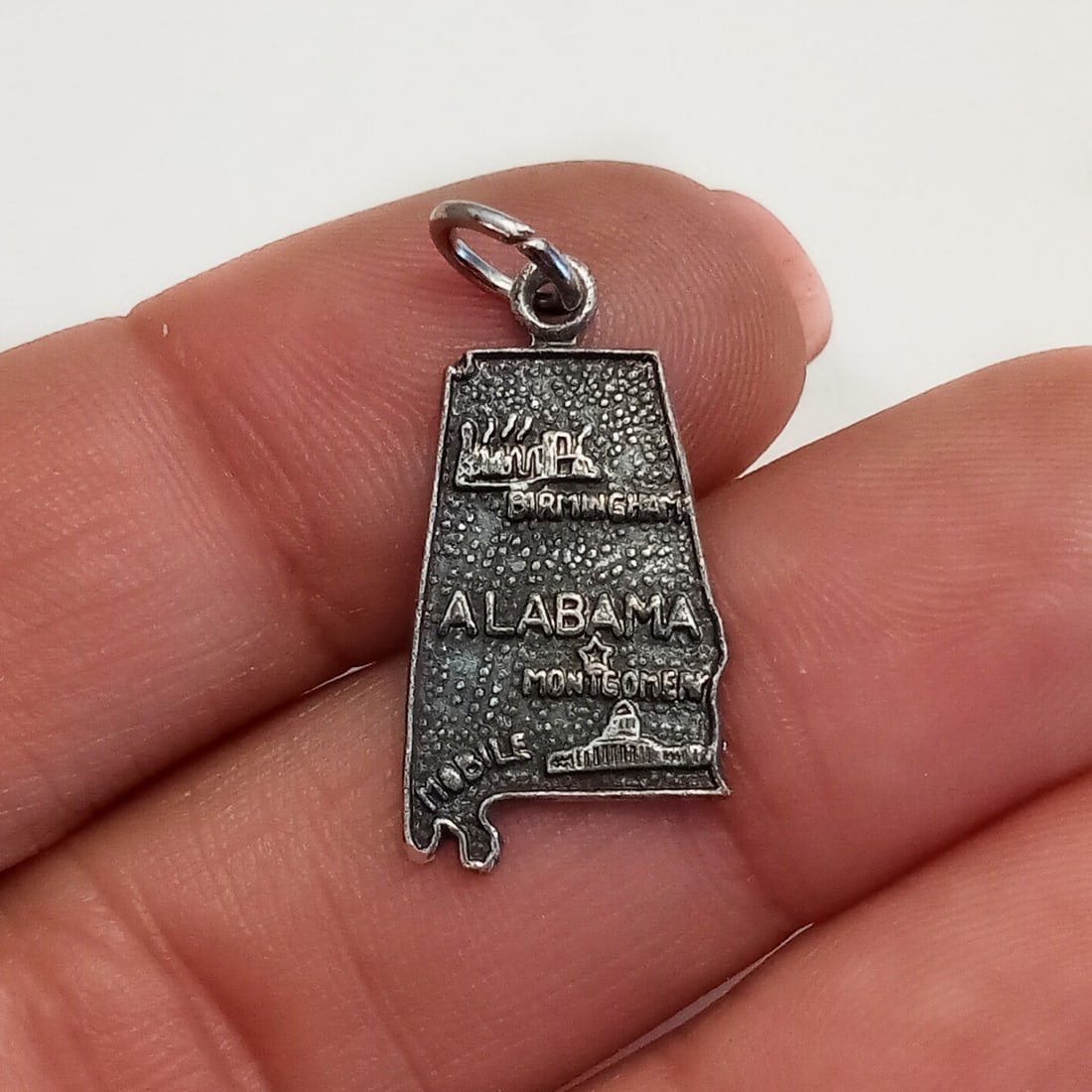 Vintage sterling silver Alabama state charm: Vintage sterling silver textured finish Alabama state charm pendant. Weight 1.41 grams. Length 1 inch with bail. Hallmarked F in circle, Sterling. Condition very good.