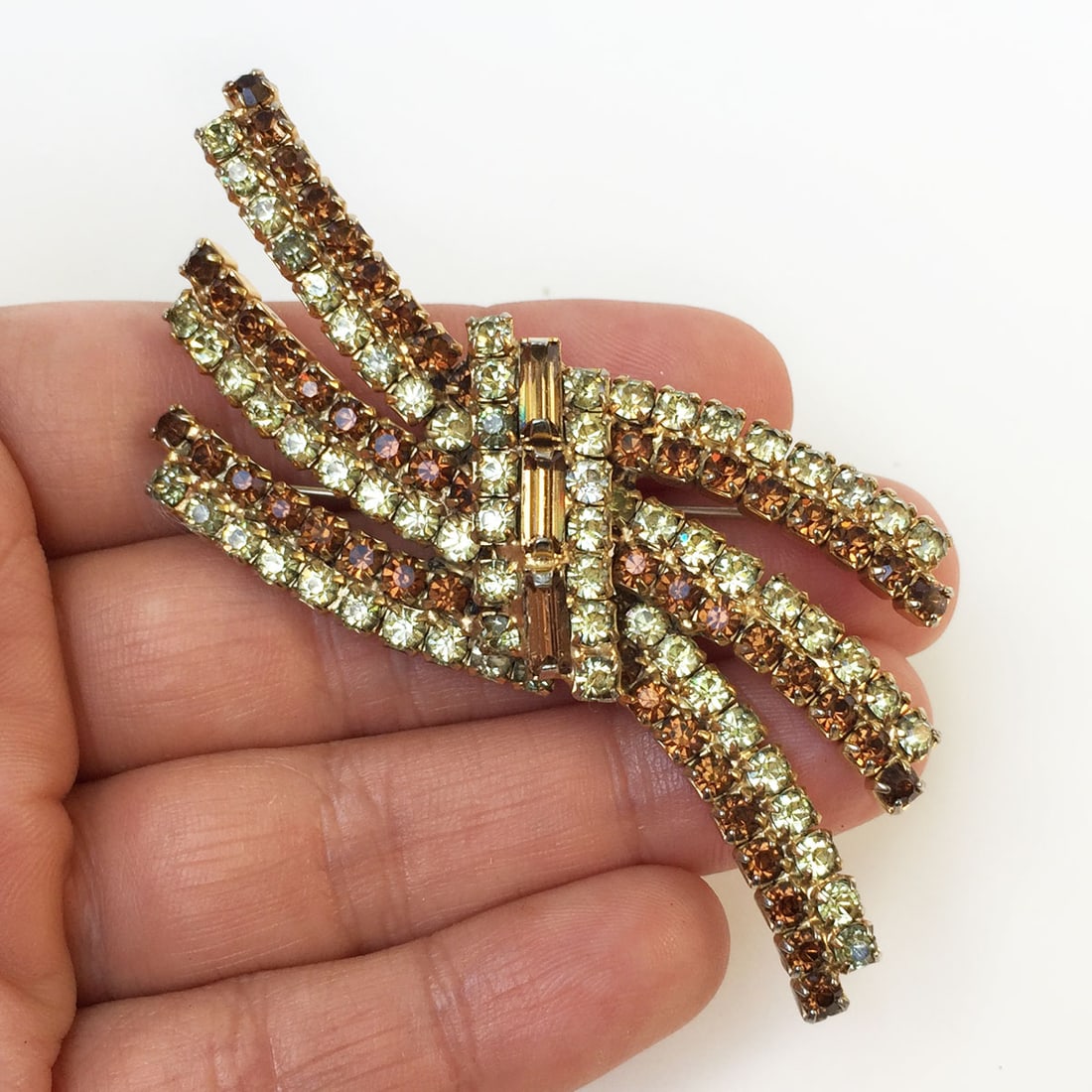 Vintage gold tone prong set crystals Bow Ribbon brooch: Vintage gold tone prong set brown and green crystals Bow Ribbon brooch. Measured 3 x 1 1/4 inches. Condition very good.