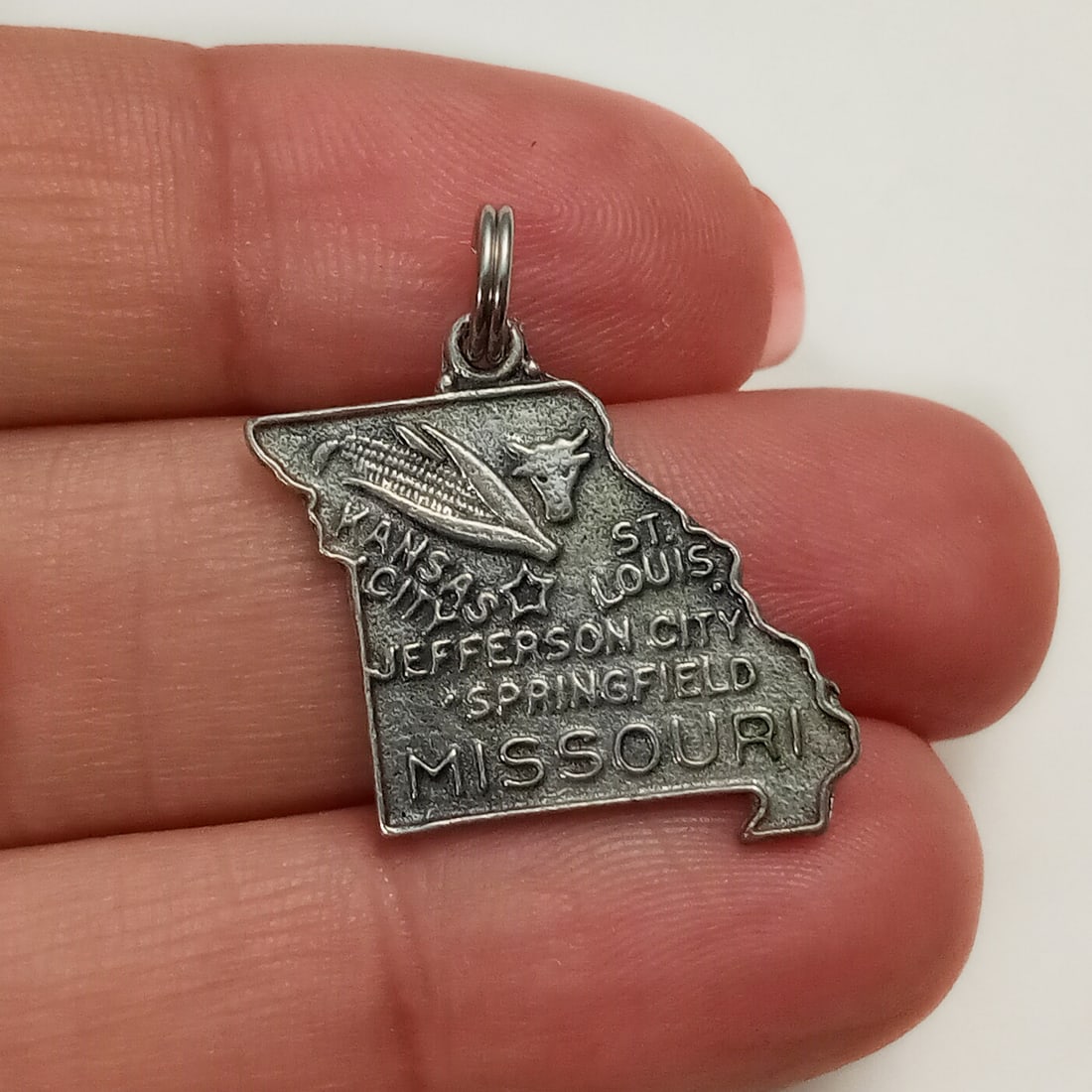 Vintage sterling silver Missouri state charm: Vintage sterling silver textured finish Missouri state charm pendant. Weight 2.71 grams. Length 7/8 inch with bail. Hallmarked Sterling. Condition very good.