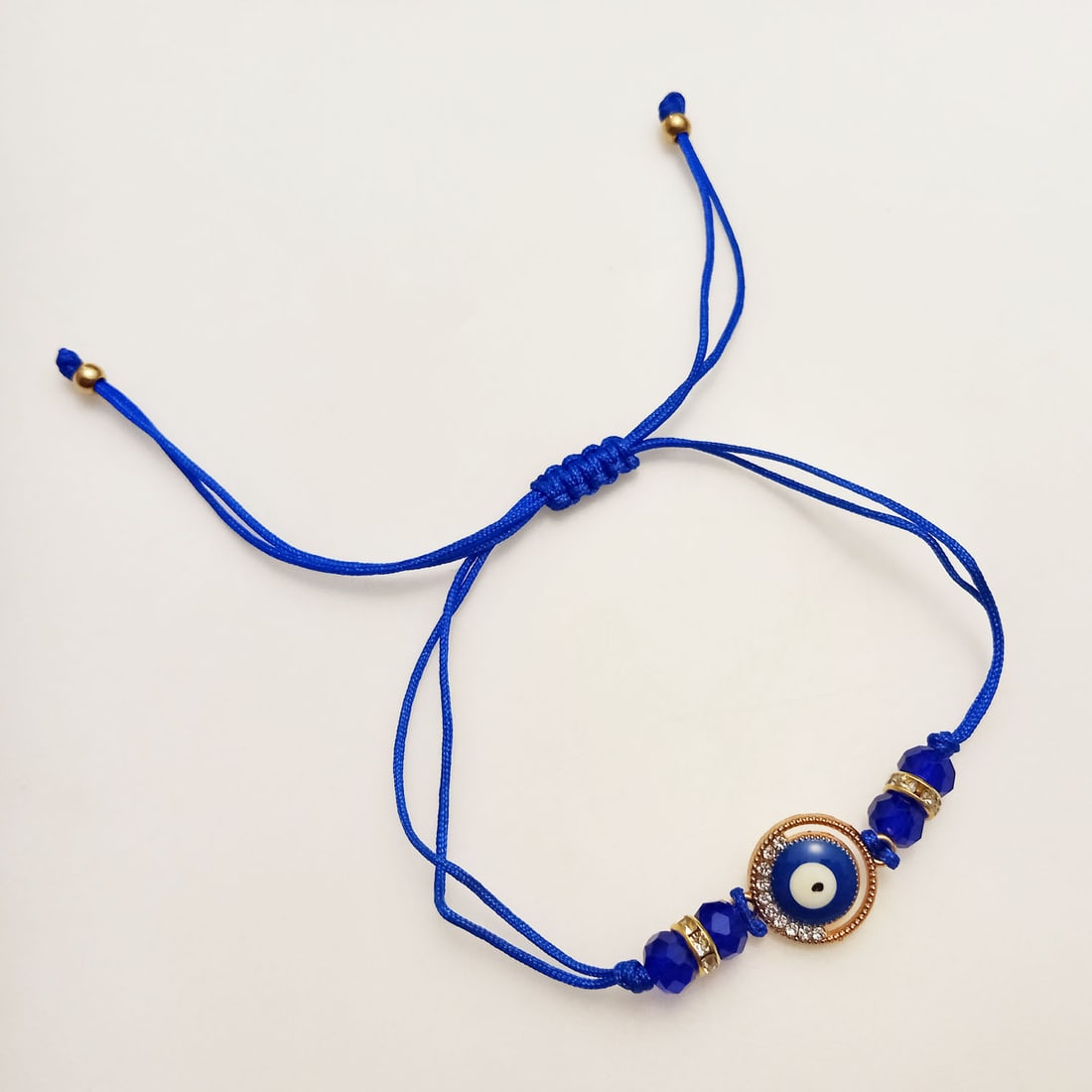 God tone rhinestones Evil eye cord adjustable bracelet: God tone clear rhinestones and blue color beads Evil eye charm adjustable bracelet. Length adjustable up to 12 inches. Evil eye charm measured 1/2 inches in diameter. Condition excellent.