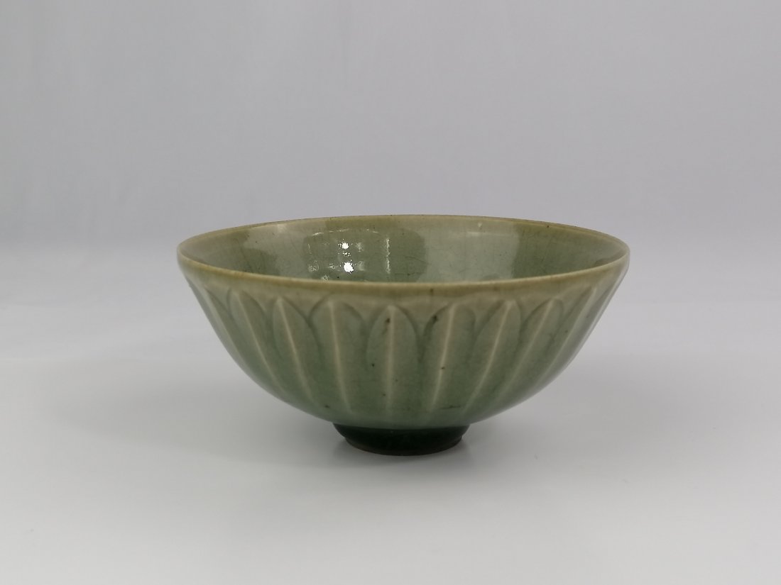 A Chinese Ming dynasty Longquan ware Celadon bowl: 16th century Chinese Ming dynasty Longquan ware Celadon bowl. The bowl is carved on the exterior with overlapping petals which radiate from the base and is covered allover in a pale olive-celadon glaz