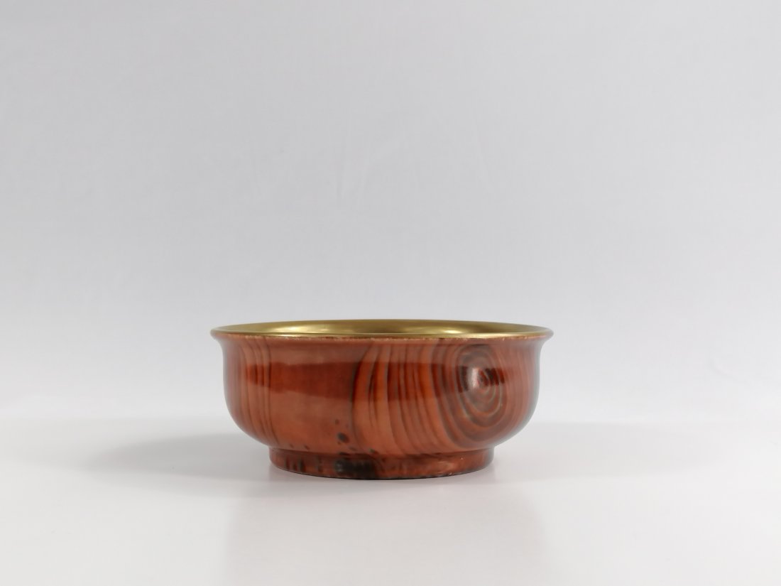 A Chinese-Mongolian Faux Bois-Enameled Bowl: 18/19th century, Qing dynasty, The bowl is covered gilt inside, and outside in faux bois enamel simulating a burlwood-like pattern. The shape in Mongolian tea bowl style. 12.9cm diameter Provenance: P