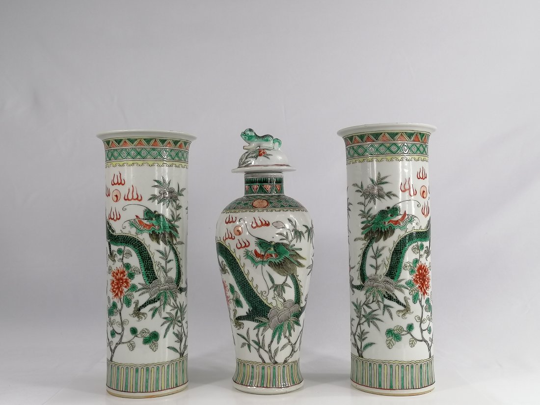 Chinese Famille Verte porcelain garniture of three vase: A Chinese famille verte porcelain garniture of three vases, mark of Kangxi but late 19th century, comprising a baluster vase and cover and a pair of cylindrical vases, each painted with a dragon chasi