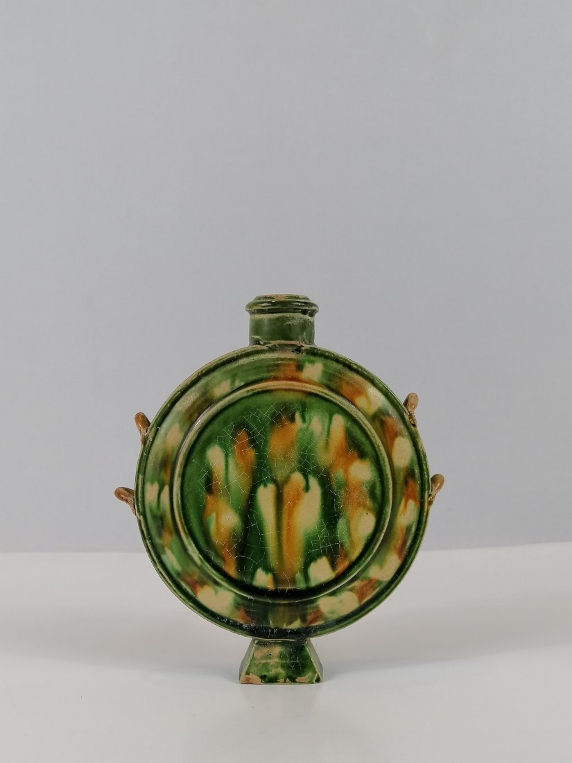 Han-style bottle with Trapezoid foot: Probably 10th century, Five dynasties, Sancai pottery flat HU, it is decorated to the shoulder with four loop handles and four moulded foliate and trapezoid foot 15.3cm tall. Provenance: Private colle
