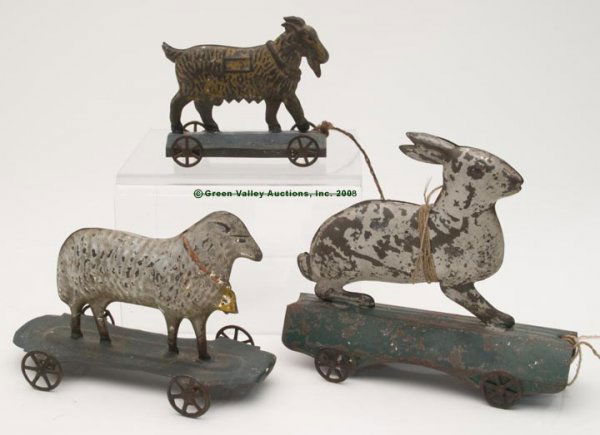 EARLY PAINTED TIN ANIMAL PULL TOYS, LOT OF THREE,: EARLY PAINTED TIN ANIMAL PULL TOYS, LOT OF THREE, full-bodied goat, sheep, and rabbit, each on a green platform base with cast iron wheels, one with pressed numbers under base. Second half 19th centur