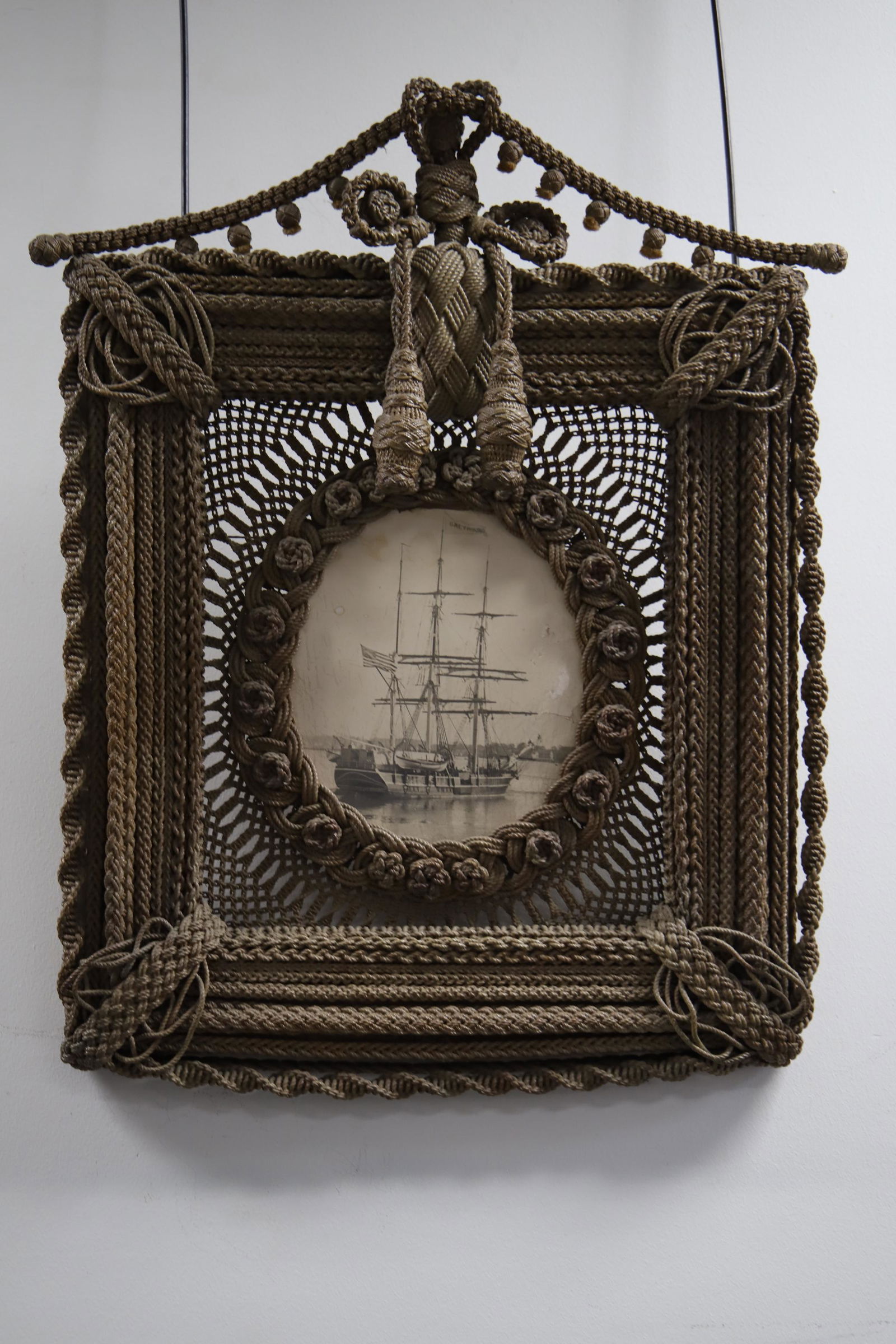 Tall Ship Photo with Sailor's Knot Frame: Tall ship photo called Greyhound; Frame made of sailor's knots; Visible area measures approximately H 11 x W 9 1/2 inches; Framed outer dimensions measure approximately H 30 x W 24 x D 2 inches; Some