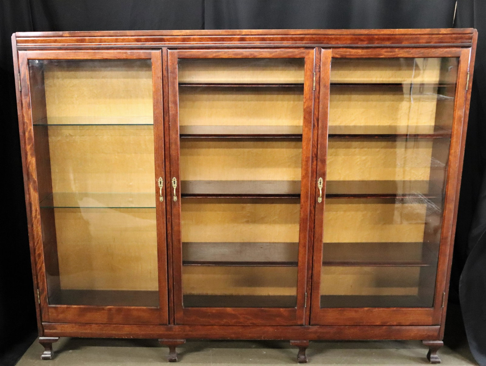 Glass Front Book Shelf: Wooden book shelf with three glass front doors; Measures approximately H 57 x W 71 x D 13 inches; Slight scratching around edges. See photos