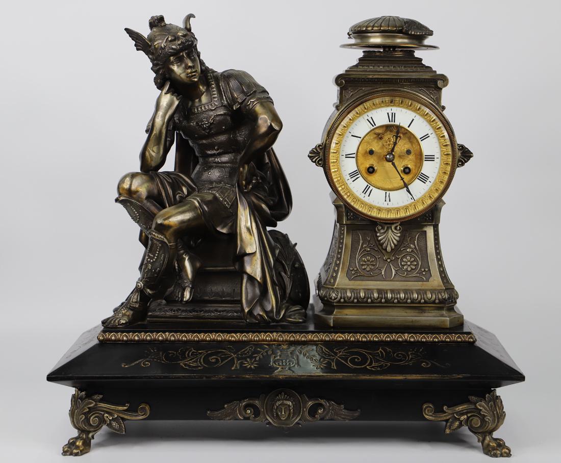 L Marti & Co, Bronze Mantel Clock: Bronze mantel clock featuring a Greek god seated next to the clock itself; Both are attached to an ornate metal base with painted gilt embellishments; Base stands on bronze claw feet; Measures approxi
