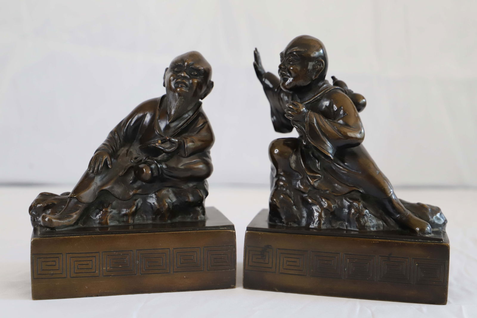 Asian Bookends: Metal bookends, possibly brass; No marks observed; Together they measure approximately H 8 x W 12 1/2 x D 3 3/4 inches; It appears that one is missing something from his hand; See photos. Pick up in D