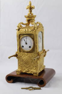 Tiffany & Co, Sedan Chair Carriage Clock: Clock marked "Tiffany & Co. Paris"; Ormolu with a porcelain dial face; Two painted portraits on each of the sides; One is signed "L Cotto"; Working condition unknown; Key is present; Measures approxim