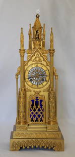 Neo Gothic Clock: Gilded brass clock depicting a cathedral façade; Dial depicts a stained glass rosette; Blue glass is loosely sitting behind door; No maker marks observed; Working condition unknown; Measures