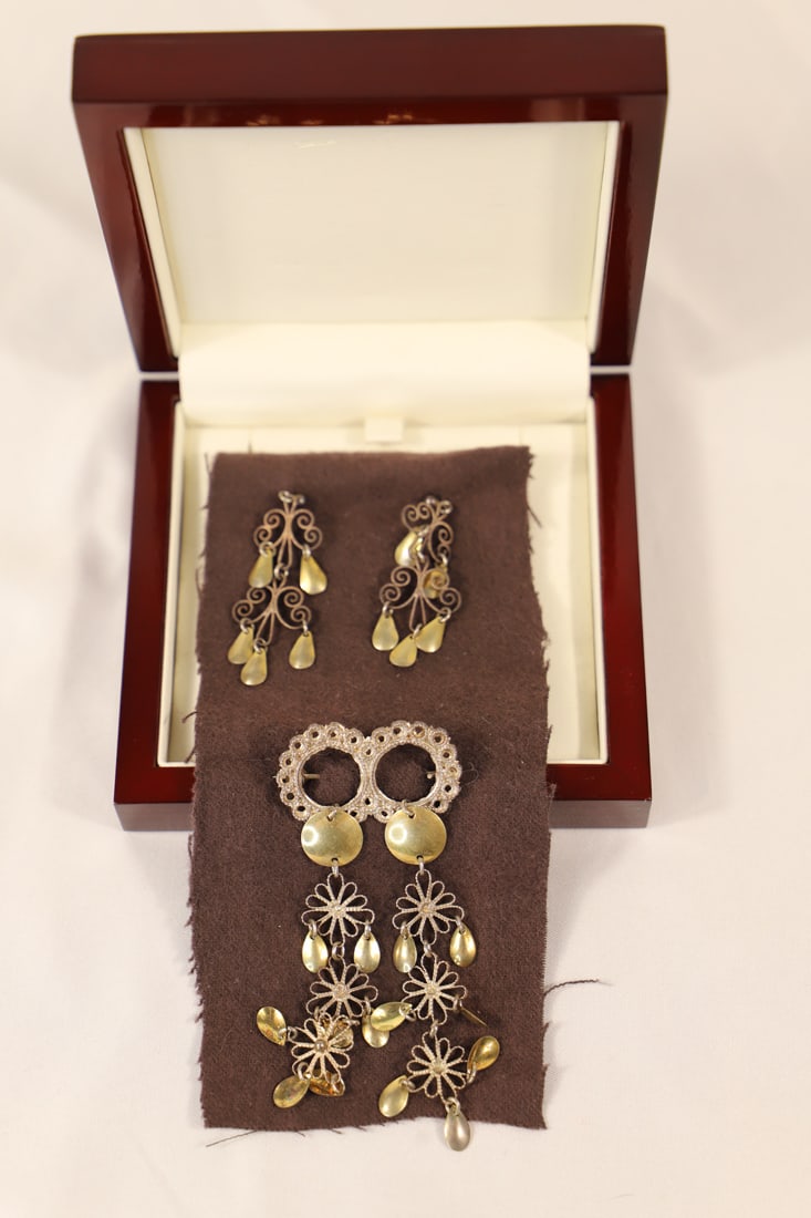 Vintage Jewelry: Vintage handmade brooch and matching earrings in a lacquered wooden box; Jewelry is silver tone scrollwork with flat gold tone disks and teardrops; No maker mark observed; Brooch measures approximatel