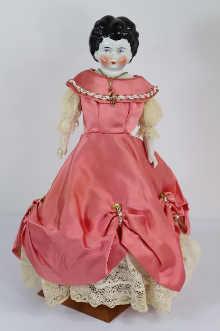 Porcelain Head Fashion Doll: Low brow porcelain head doll with porcelain legs, feet and club hands; Lace hoop slip and satin dress; Painted shoes and ribbon ties on legs; No maker mark observed; Measures approximately H 16 inches