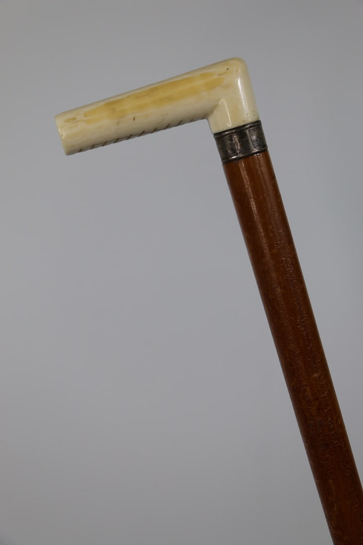 Bone Handled Cane: Antique walking stick / cane with bone handle and sterling silver collar; Underside of handle is carved; Measures approximately H inches; Bone on handle has old crack; Collar is tarnished; Shellac on