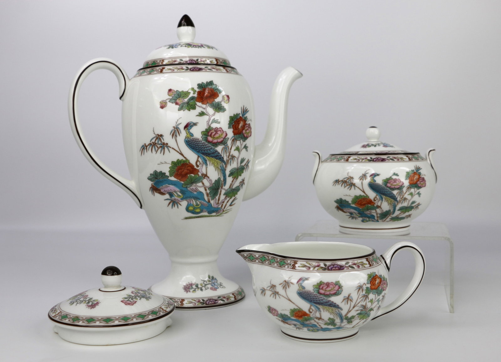 Wedgwood, Coffee Pot, Cream, Sugar: Coffee pot, creamer, sugar with lid and one teapot lid; All in the Kutani Crane pattern; Number R4464; Coffee pot measures approximately H 10 x W 9 x D 4 1/2 inches; In used condition; Sugar bowl has 