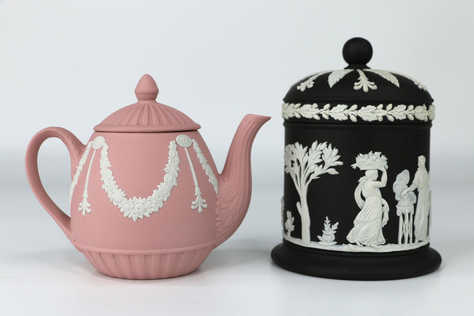 Wedgwood, Jasperware: Lidded black trinket dish; possibly a cigarette jar; Miniature pink teapot; Both are marked "Wedgwood, Made in England"; Teapot measures approximately H 3 1/2 x W 5 x D 3 inches; Small chip on inside