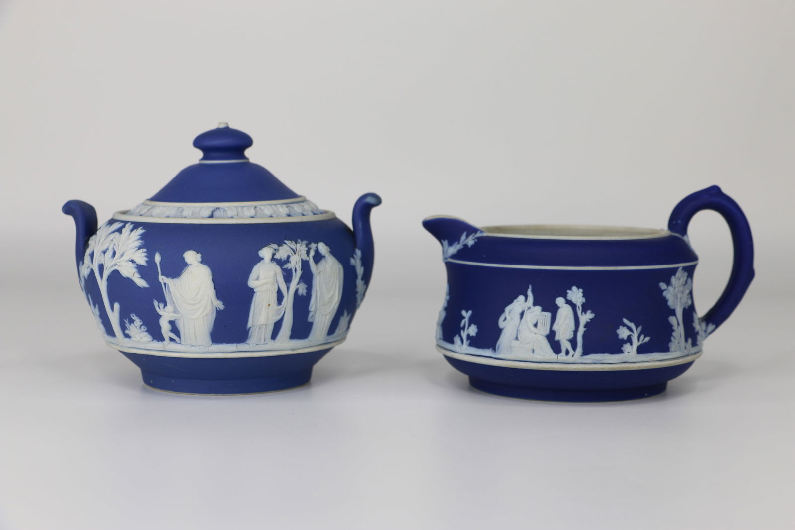 Wedgwood, Jasperware: unmatched cobalt blue cream and sugar; Both are marked "Wedgwood, England" on the bottoms; Creamer measures approximately H 2 3/4 x W 4 3/4 x D 3 1/2 inches; Slight discoloration on both pieces. See p
