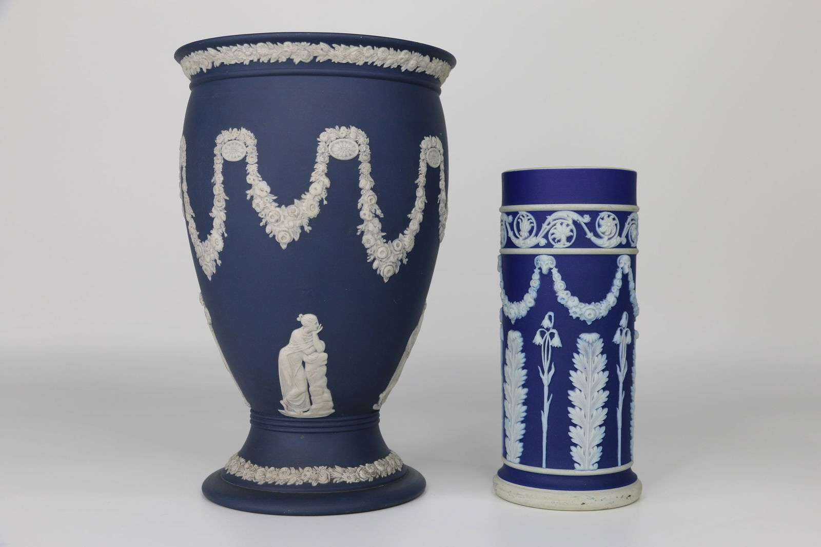 Wedgwood, Jasperware: Two cobalt blue vases; Both are marked "Wedgwood, England"; Smallest measures approximately H 7 3/4 x Diameter 5 inches; Relief work is very dirty/dusty on the largest piece; Scuff marks on bottom whi