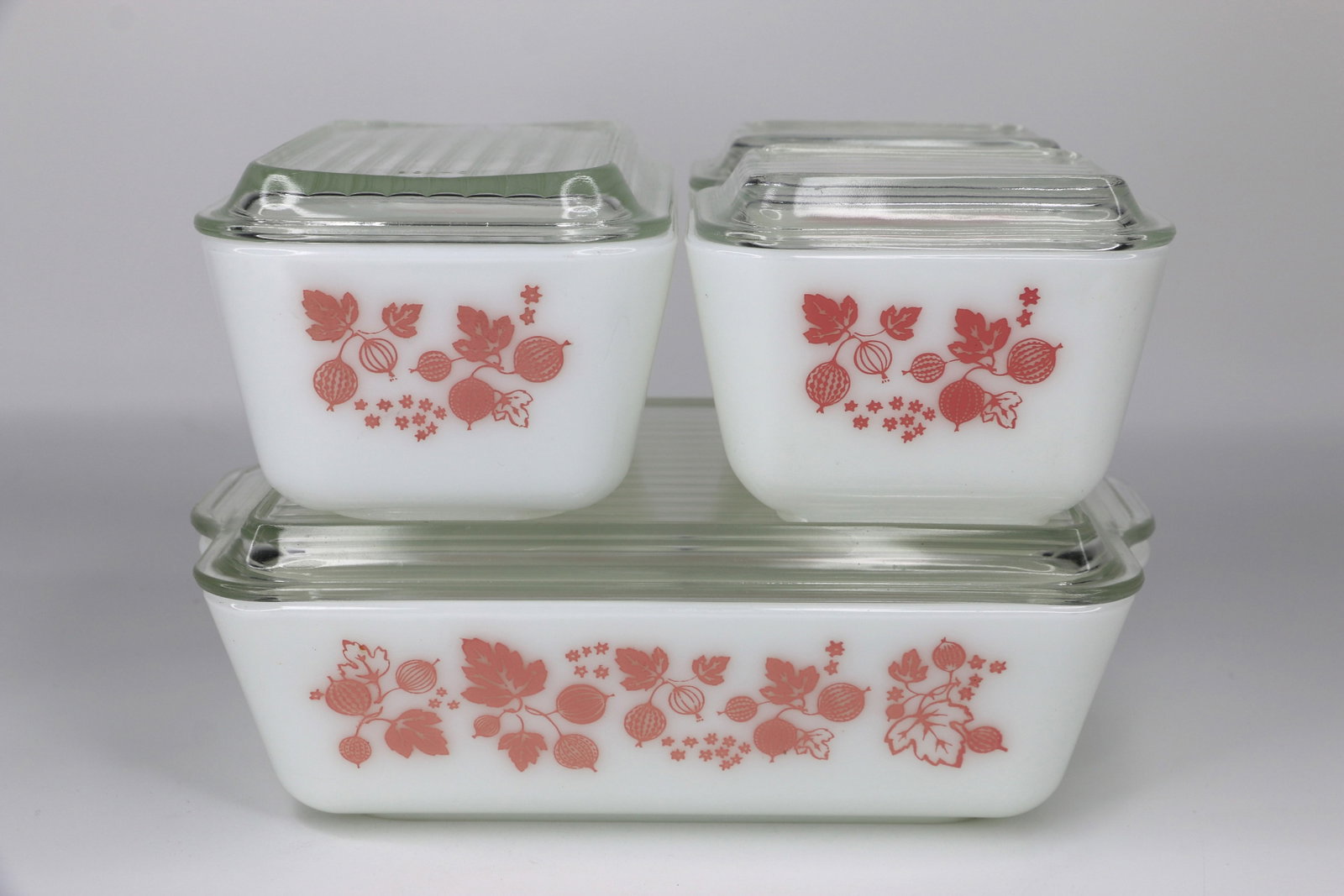 Pyrex, Refrigerator Boxes: Four stacking jars with lids; In the pink gooseberry pattern; Numbered on the bottoms 501, 501, 502, 503; Smallest box measures approximately H 3 x W 4 1/2 x D 3 1/2 inches; Very small chips on inside