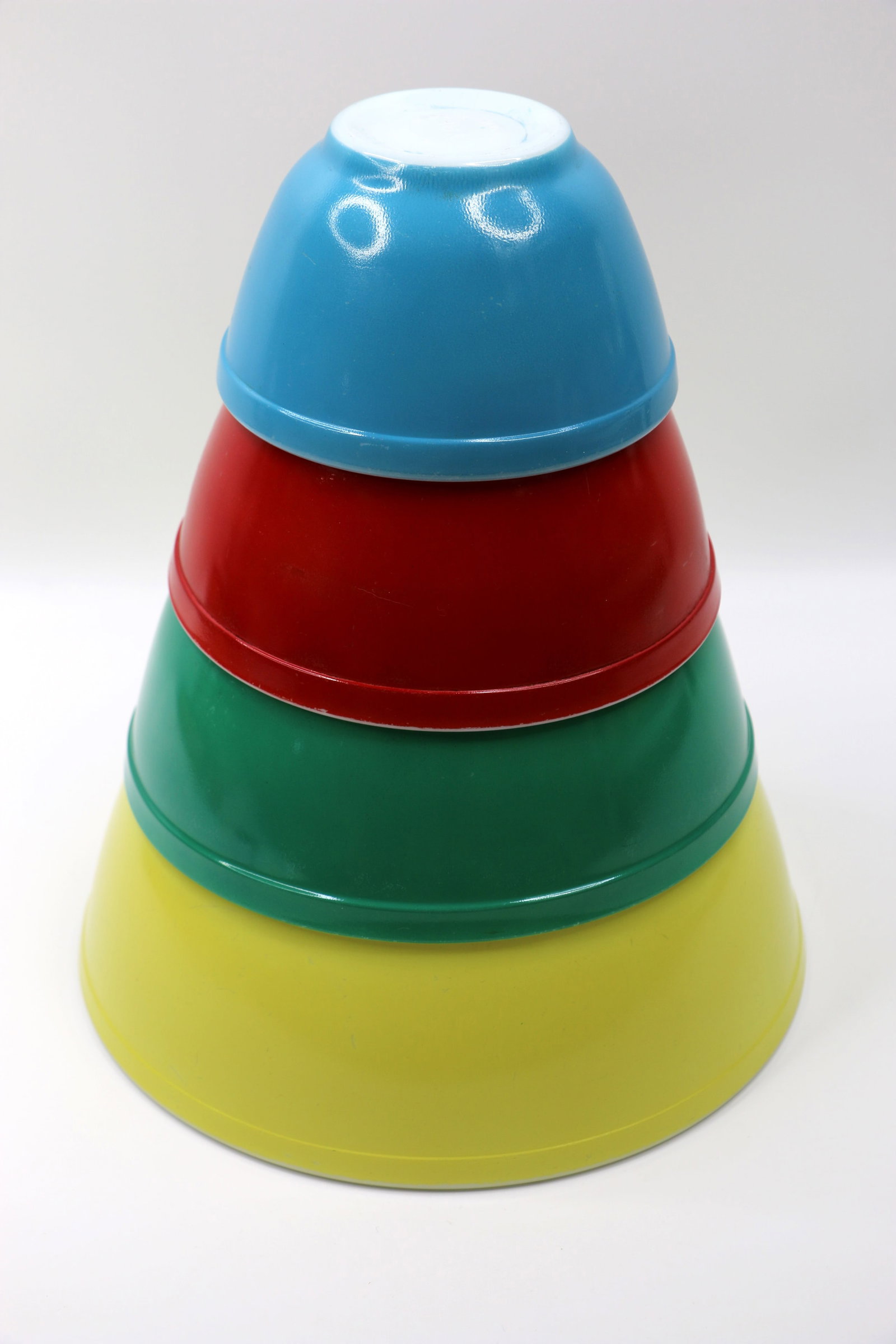 Pyrex, Mixing Bowls: Four nesting bowls; Red is numbered 402, green 403, yellow 404; No number on small blue bowl; Largest measures approximately H 4 1/2 x Diameter 10 1/2 inches; In used condition; scratches on bowls; Co