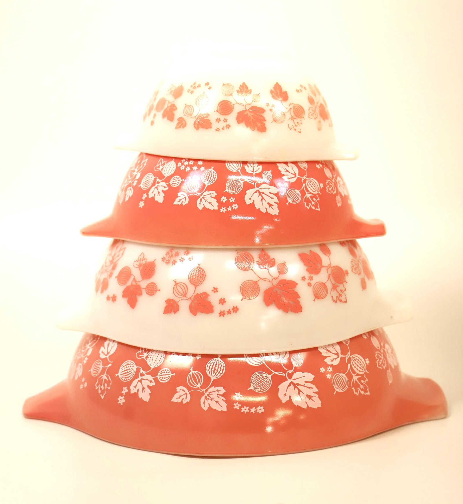Pyrex, Nesting Bowls: Four bowls with handles; In the pink gooseberry pattern; Bowls are numbered 441, 442, 443, 444; Largest bowl measures approximately H 4 1/4 x W 13 x D 10 1/2 inches; Utensil marks / scratches in all b