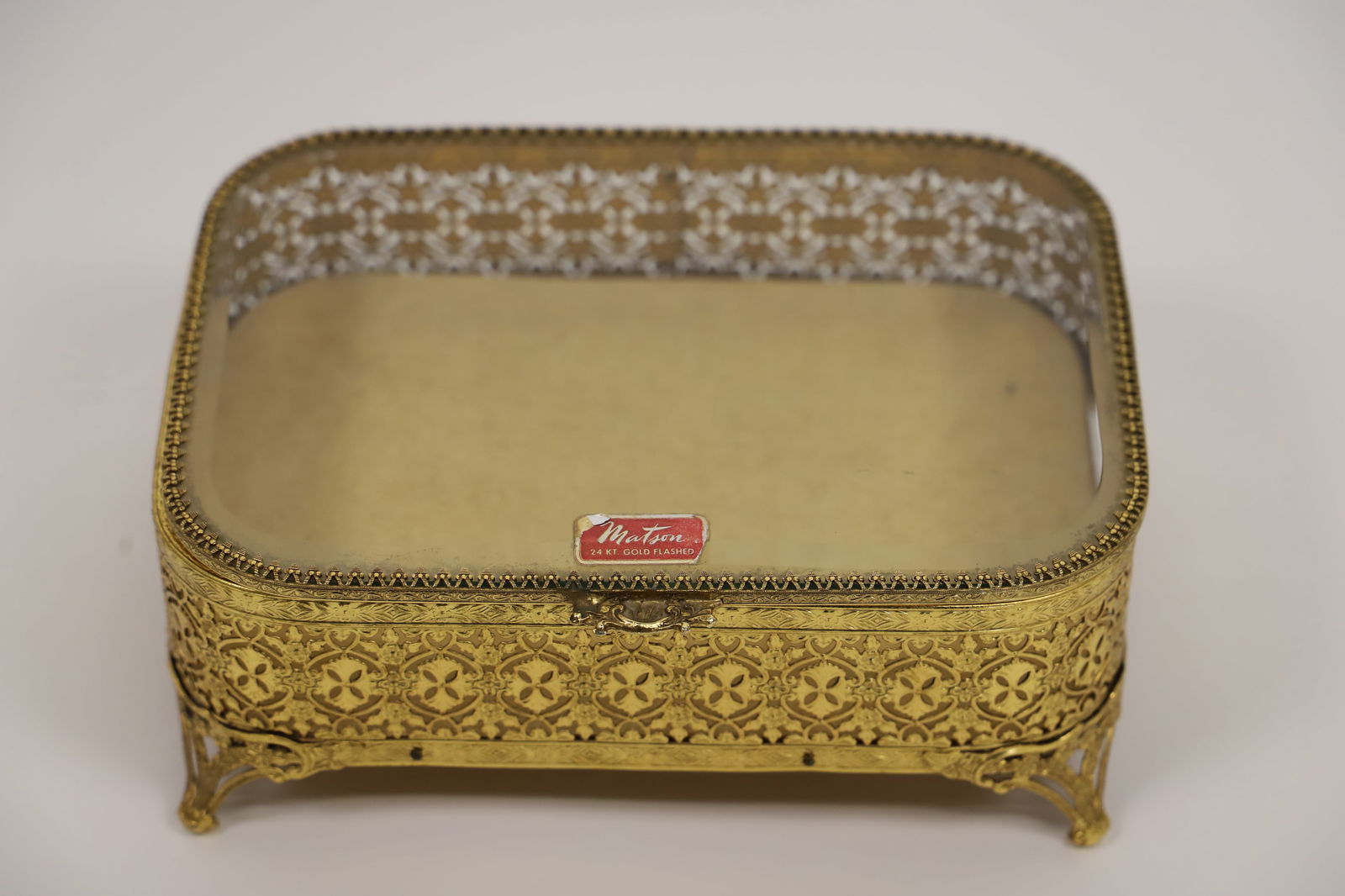 Matson, Jewelry Casket: Ormolu filigree jewelry box with beveled glass lid; Measures approximately H 3 x W 7 3/4 x D 6 1/4 inches; Stains on fabric. See photos