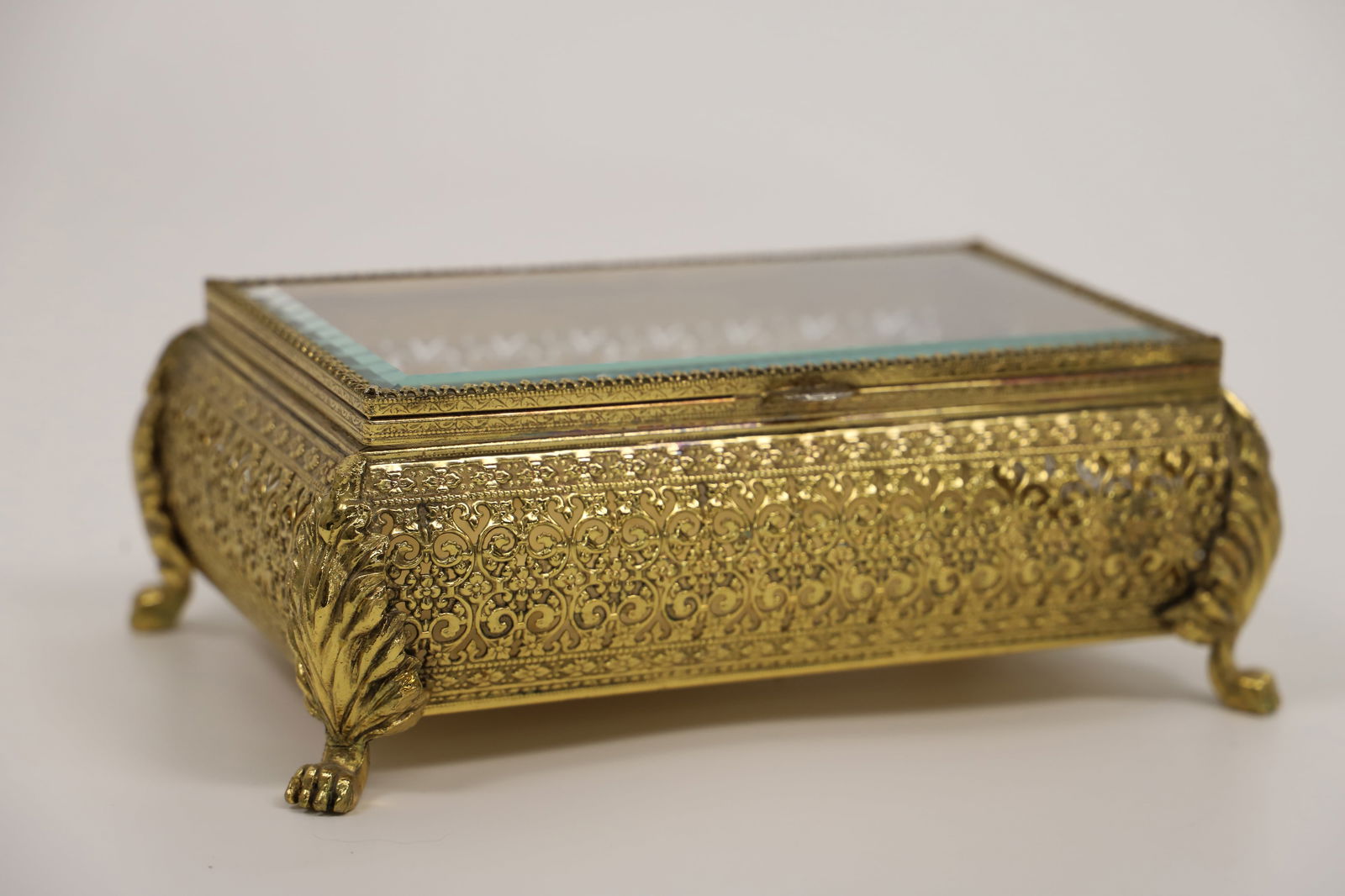 Vintage Jewelry Casket: Ormolu filigree jewelry box with beveled glass lid; No maker mark observed; Measures approximately H 3 x W 7 1/4 x D 5 inches; Fabric bottom is loose. See photos