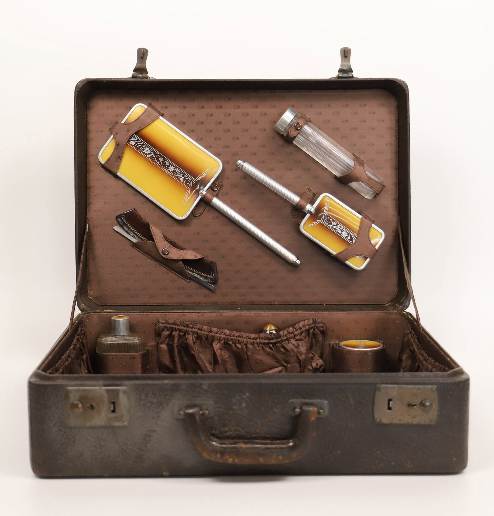 Dressing Vanity Suitcase: Vintage leather suitcase housing a vanity set; No maker marks observed; Case measures approximately H 5 1/2 x W 17 1/2 x D 12 inches; Comb is not original to the set; Leather is damaged. See photos