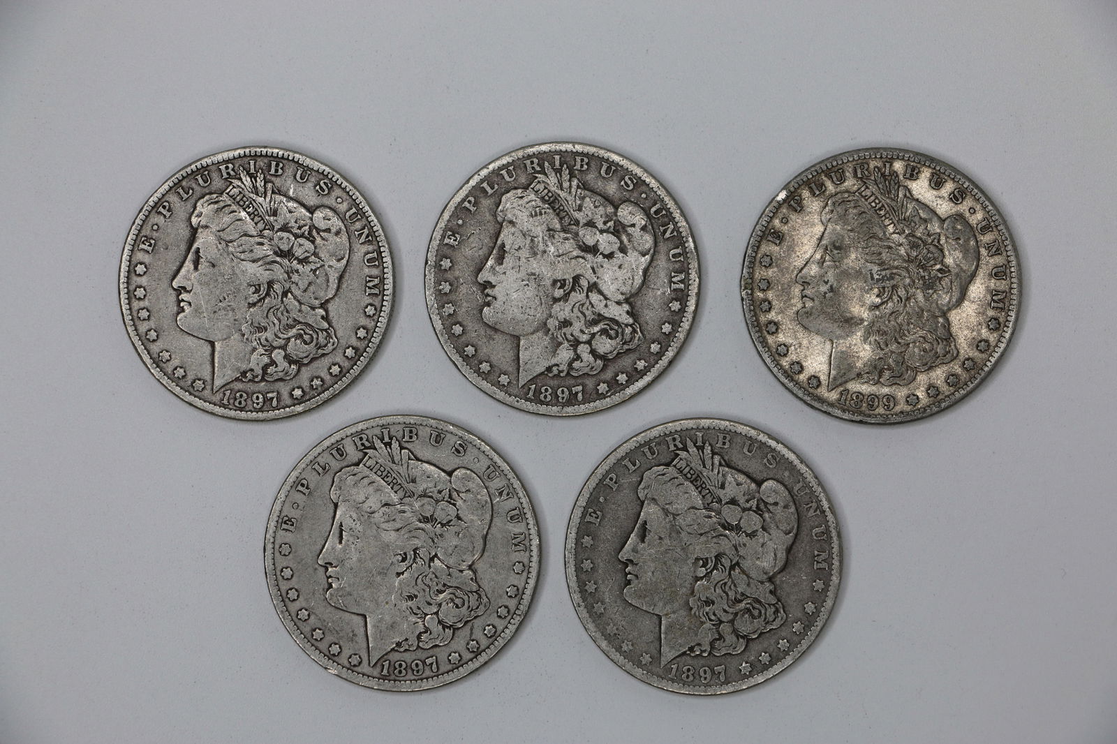 Morgan Silver Dollars: Five "O" circulated silver dollars; Four are dated 1897; One is dated 1899; Total is approximately 4.210 troy ounces;See photos