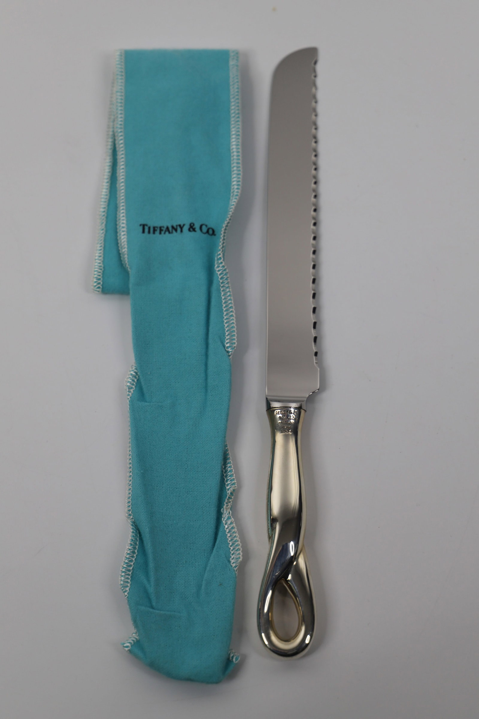 Tiffany & Co. Peretti, Knife: Bread knife with sterling silver handle; Marked "Peretti, T&Co., Sterling, Italy, 1984"; Designed by Elsa Peretti; Weighs approximately 3.345 troy ounces; Tiffany blue cloth bag has tear on one side. 