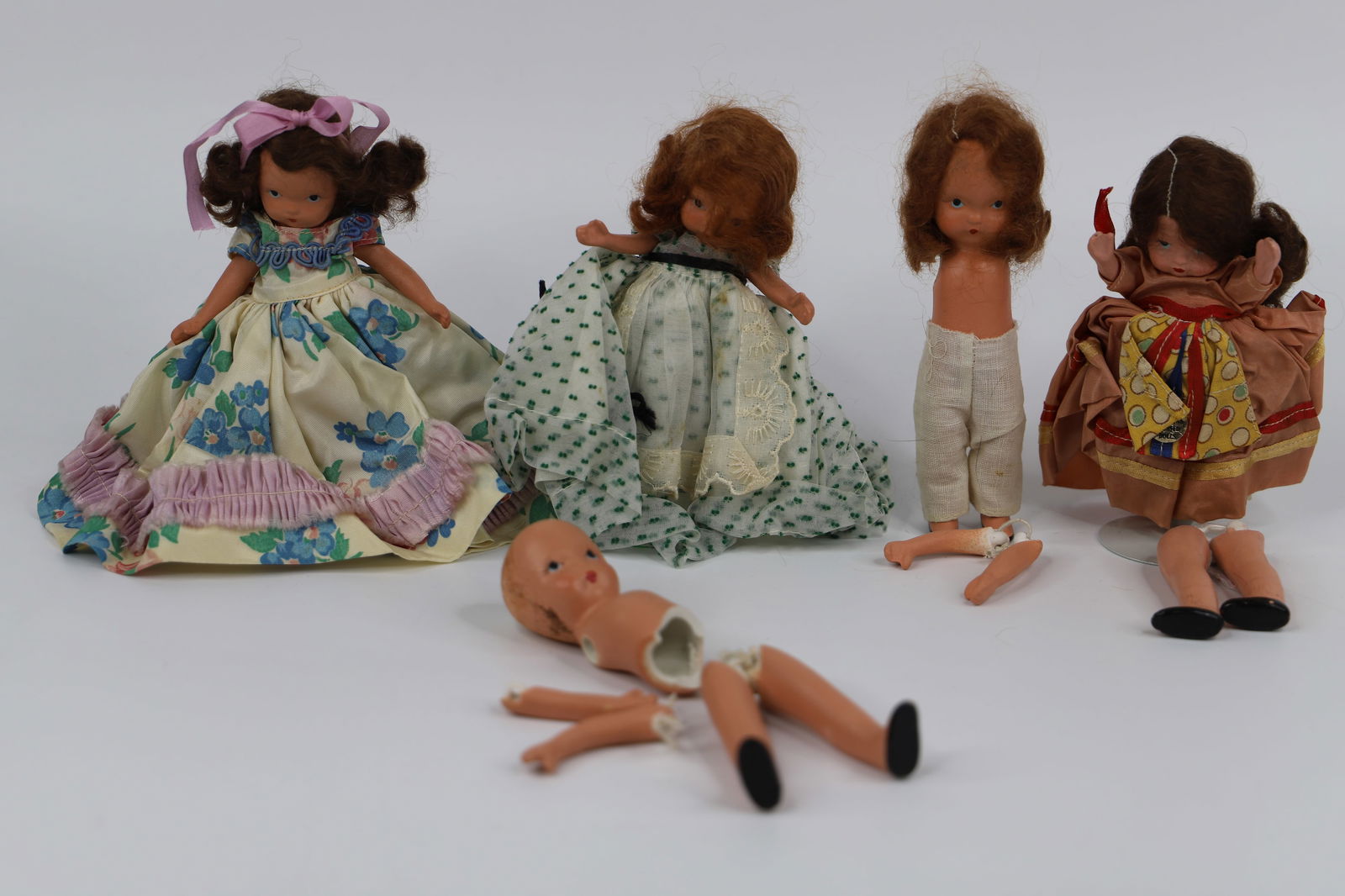 Nancy Ann Storybook Dolls: Five vintage bisque dolls; Doll with green dress measures approximately H 5 inches; Two have unattached arms and legs; One has broken torso with unattached arms and legs. See photos